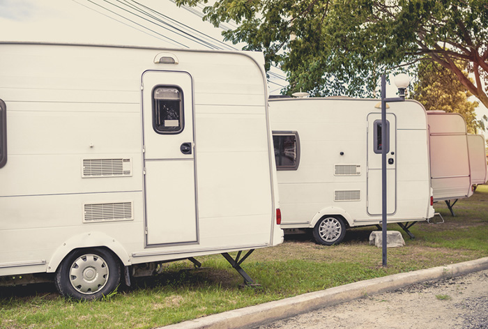 White caravan camping trailer cars, motorhomes parking in the garden.